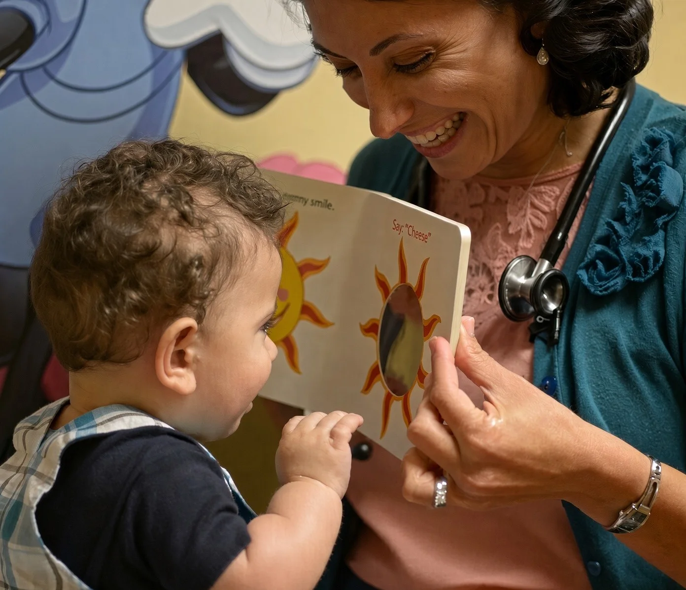 Lydia Elias, DO, sharing a picture book with a smiling baby